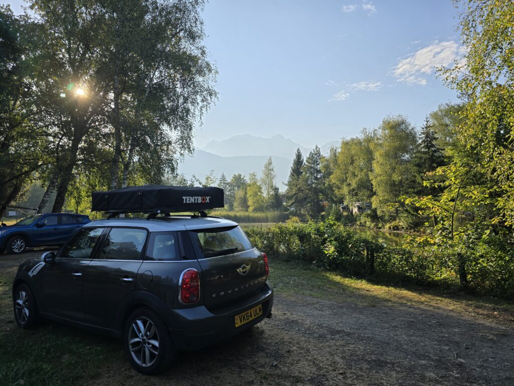 An image of a mini with a rooftent and a mountain in the background